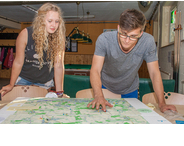 Thumbnail zum Artikel über die Sozialraumanalyse - zeigt zwei Studierende, die über eine mit Markierungen versehene Karte gebeugt sind.