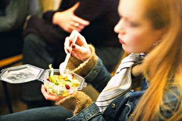 junge frau die einen salat aus plastikgeschirr ist